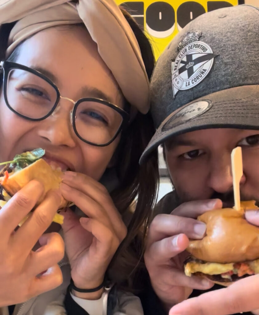 A smiling couple taking a bite into their egg sammies at a dog-friendly brunch spot in Dublin.